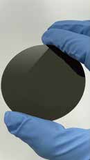 A dark boron-doped diamond disc held in gloved hands.