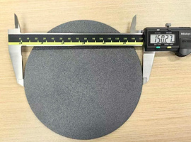 A polycrystalline diamond wafer on a bench with calipers reading 150 mm across it.